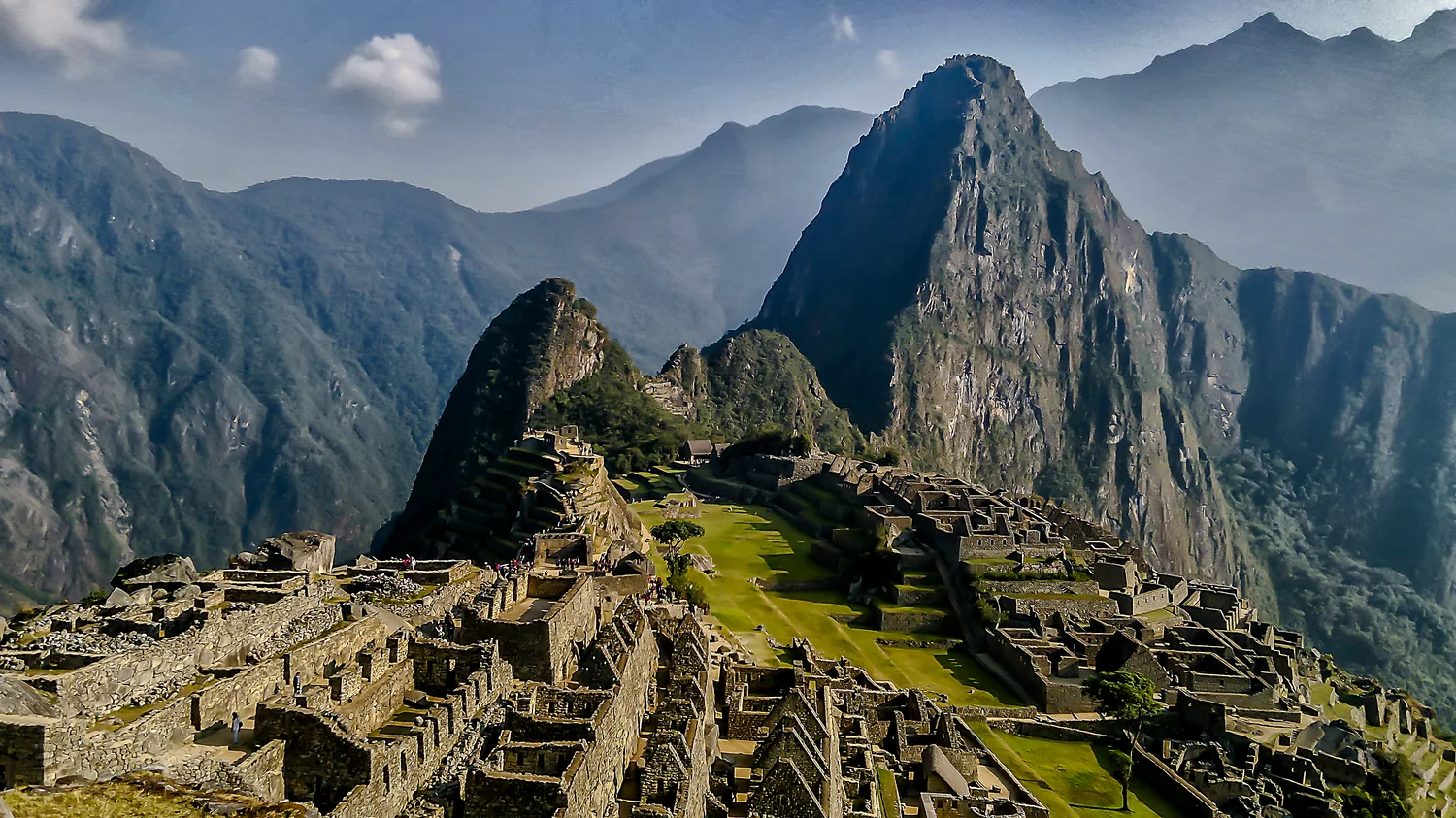 Construcciones de piedra de Machu Picchu con Huayna Picchu y montañas al fondo. Fotografía de archivo de 2012.