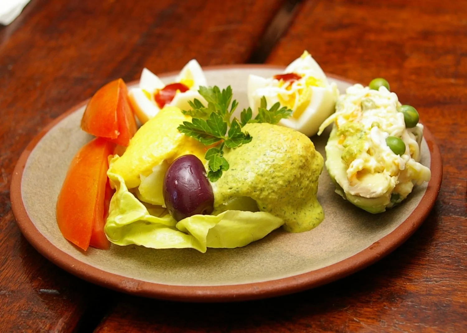 Plato de ocopa con papas cubiertas de salsa, aceituna y acompañamientos. Fotografía de archivo de 2008.